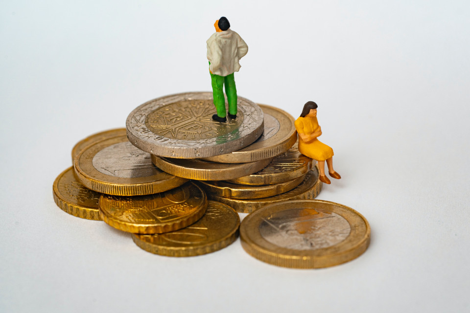 Auf einem kleinen Stapel mit Münzen stehen zwei Modellbahnfiguren. Foto: Matthieu Stern