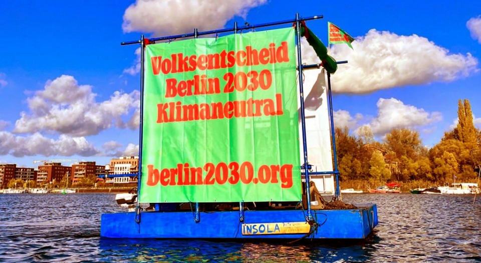 Ein Fluß auf der Spree mit einem Transparent "Volksentscheid Berlin 2030 Klimaneutral"