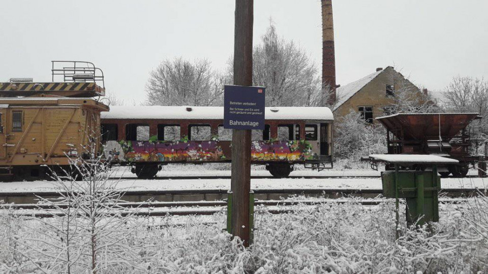Blick auf die Bahnanlagen in Seeligenstädt mit einem ausgebrannten Personenwagen und dem Schild am Bahnsteig "Bahnanlage". Foto: EFWO