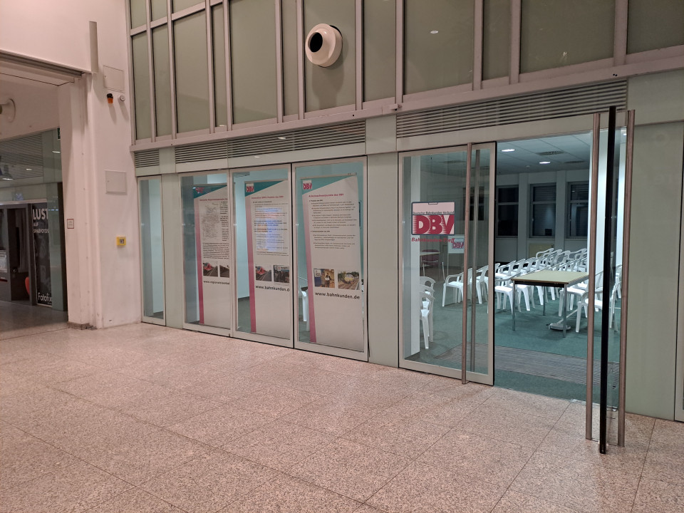 Foto der Schaufensterfront im Berliner Ostbahnhof. Neben drei Rollups mit DBV-Werbung steht eine Tür offen und gibt den Blick auf den Raum frei.