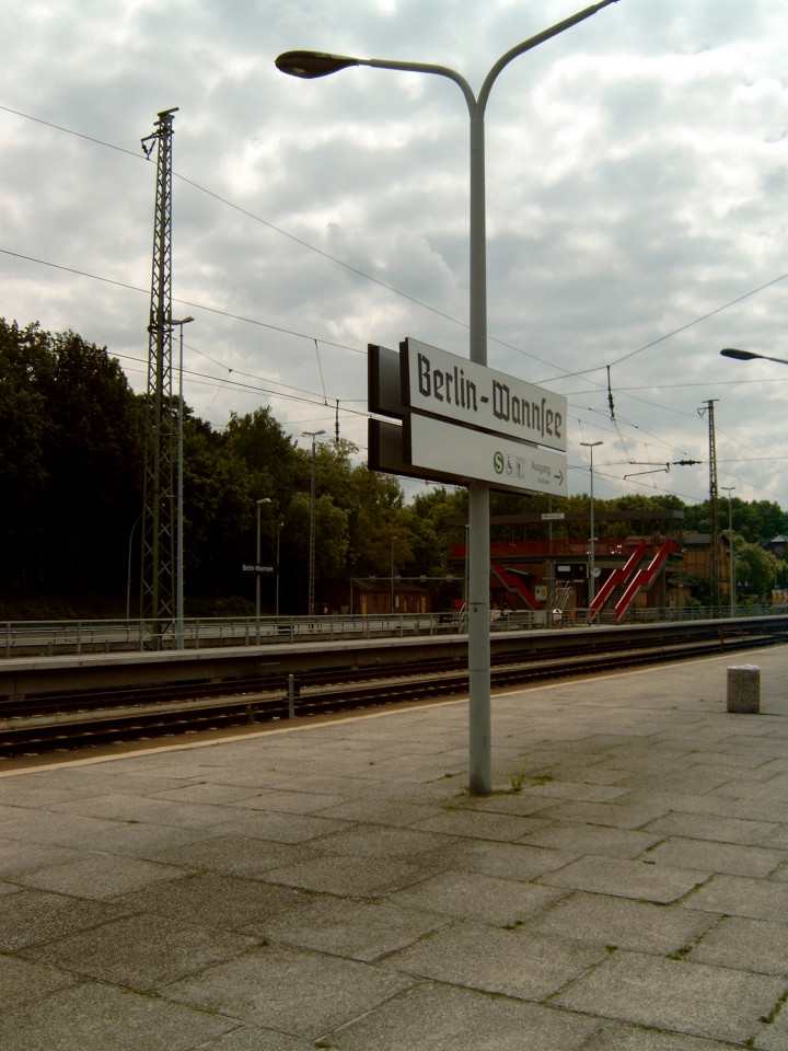 Der Fernbahnsteig im Bahnhof Wannsee mit einem Stationsschild. Im Hintergrund ist der erwähnte ehemalige Bahnsteig für die Autoreisezüge mit der Treppe erkennbar. Foto: DBV-Archiv